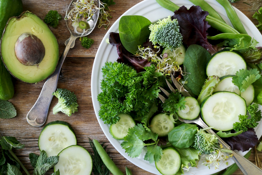Salad greens with cucumber and avocado in a bowl  and chopping board
